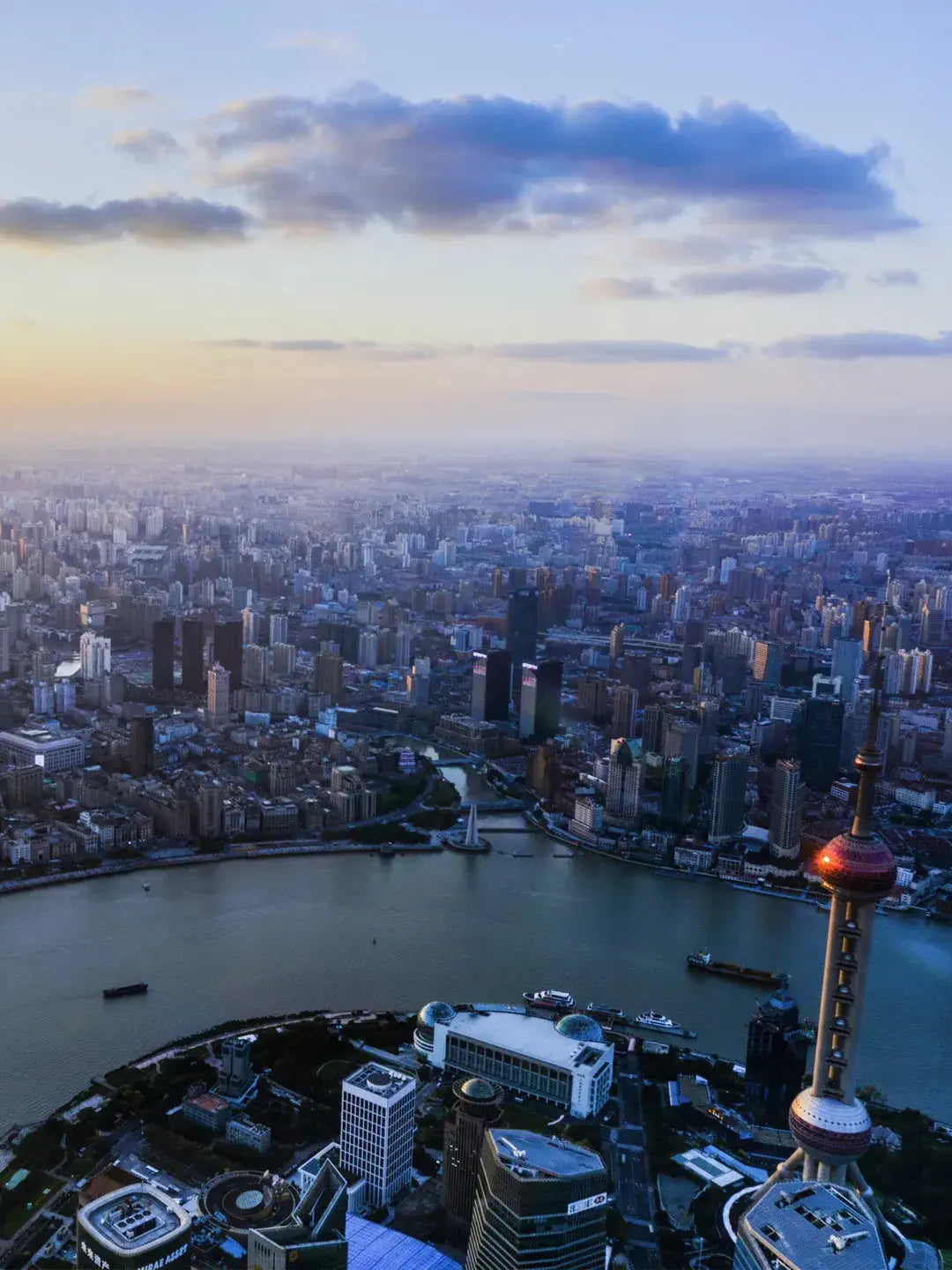 Huangpu River sunset view in Shanghai with cargo ships and Lujiazui skyline silhouette