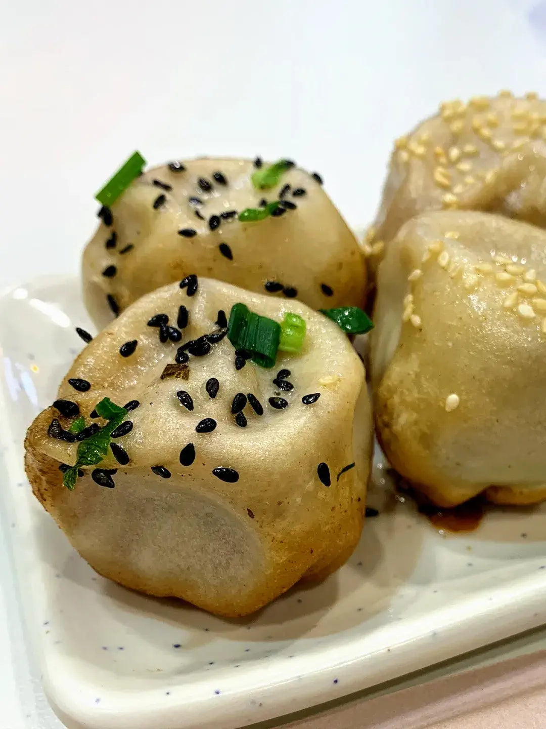 Shanghai Shengjianbao pan-fried pork buns close-up, crispy base and juicy filling