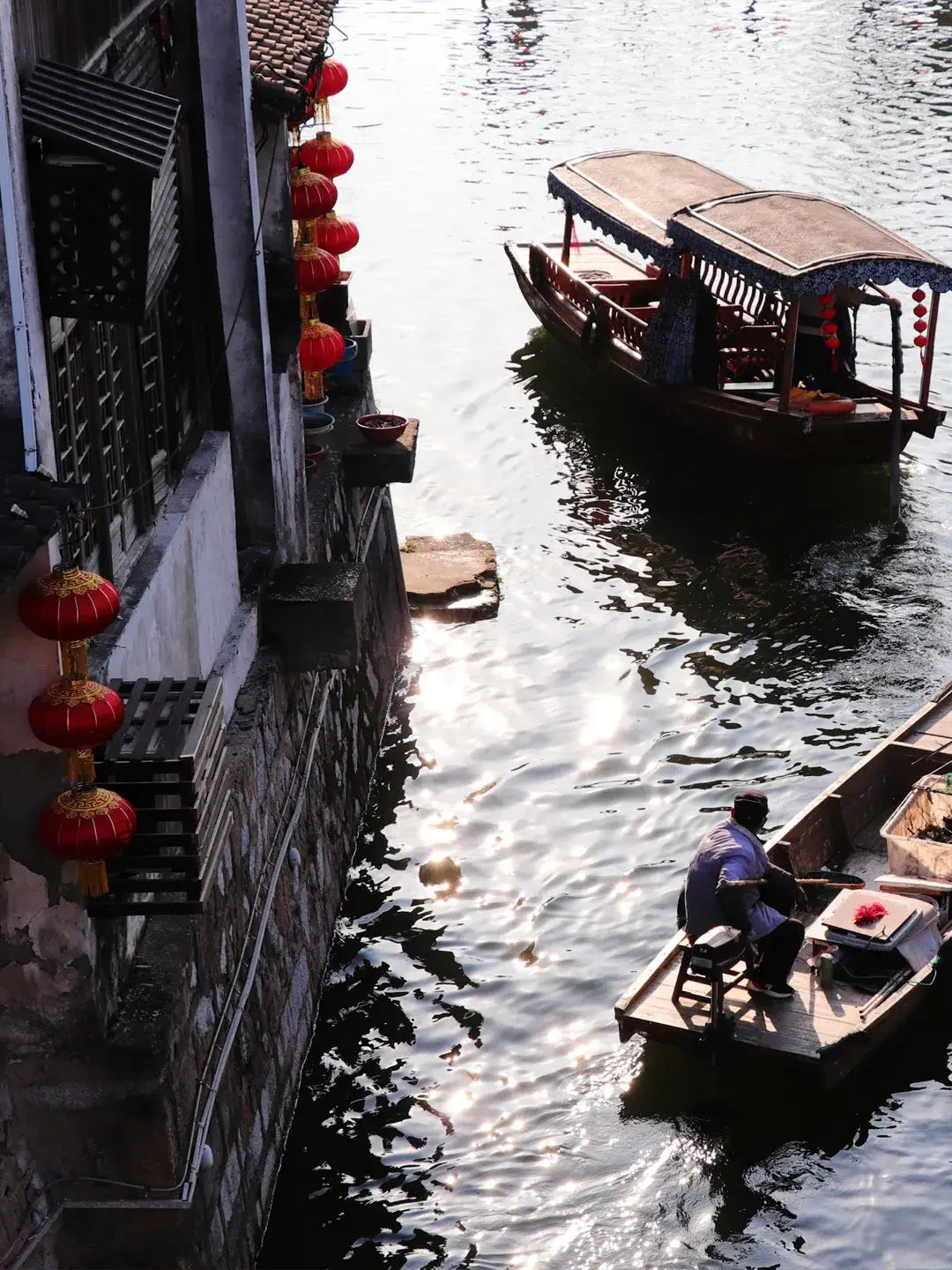 Tourists taking wooden boat ride in Nanxun, boatman in straw hat and traditional clothing